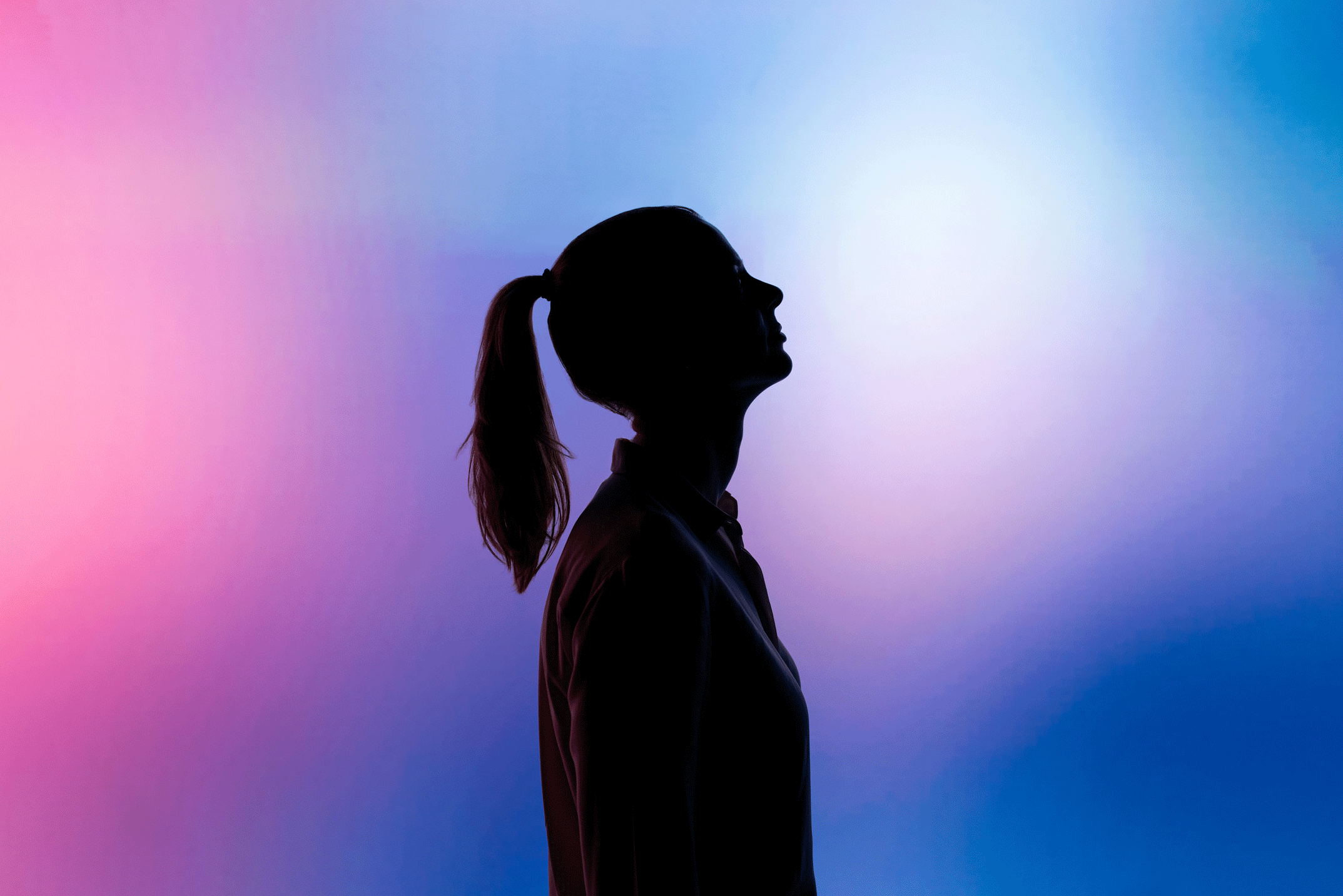 Background shilouette of a woman in a pink and purple gradient room.